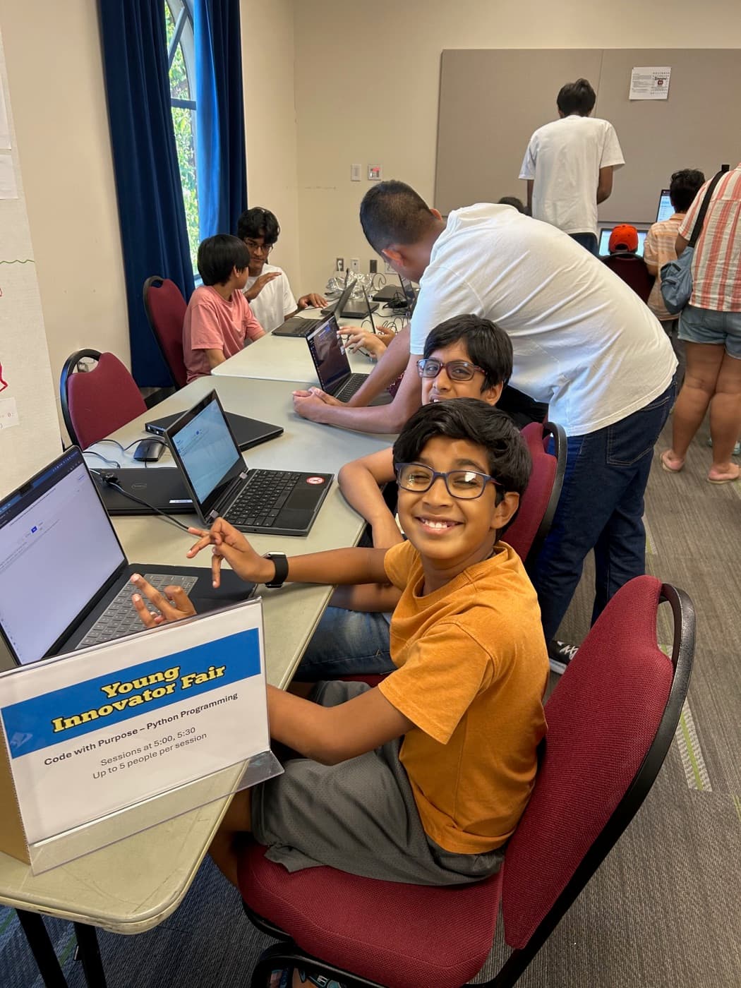 A student smiling at his laptop during a CodeWithPurpose class