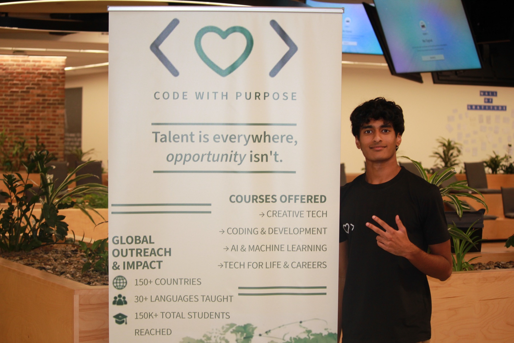 A student stands beside a CodeWithPurpose banner at the Dublin hackathon